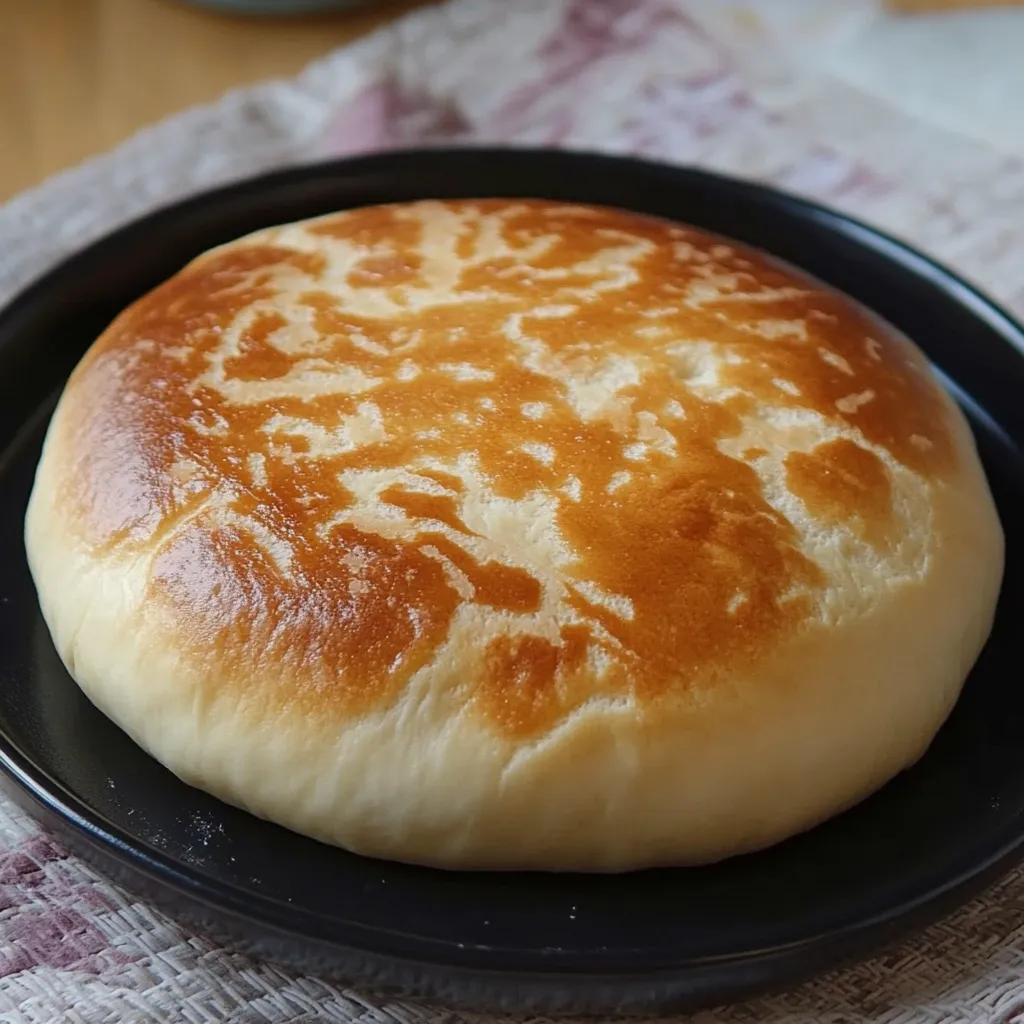 Pan casero en sartén recién hecho y dorado sobre un plato. Masa reposando antes de cocinarse en sartén. Pan casero en sartén partido por la mitad mostrando su textura esponjosa.