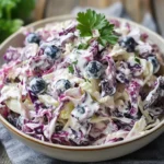 Ensalada de repollo con yogur griego y arándanos servida en un bol de cerámica.