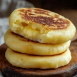 Arepa de queso colombiana dorada en sartén servida con aguacate