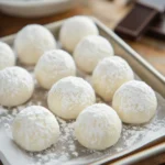 Bombones de leche en polvo caseros servidos sobre una bandeja blanca con coco rallado