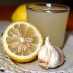 vaso con jugo de ajo y limón fresco sobre una mesa con fondo de ingredientes naturales