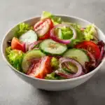 Ensalada griega servida en plato blanco con tomates, aceitunas y queso feta