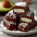Barritas saludables y nutritivas de coco bañadas en chocolate oscuro sobre papel manteca