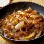 Cebolla caramelizada en sartén, dorada y brillante, lista para servir